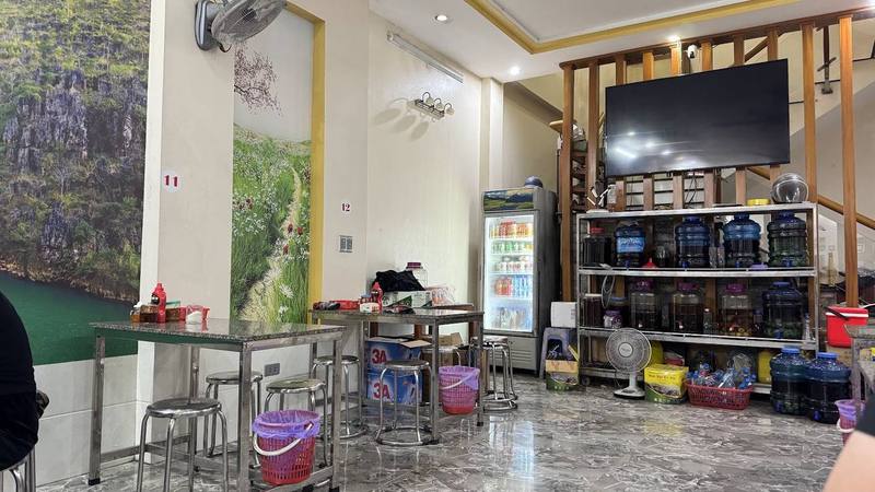 Bên trong quán với bàn inox và tranh phong cảnh Hà Giang